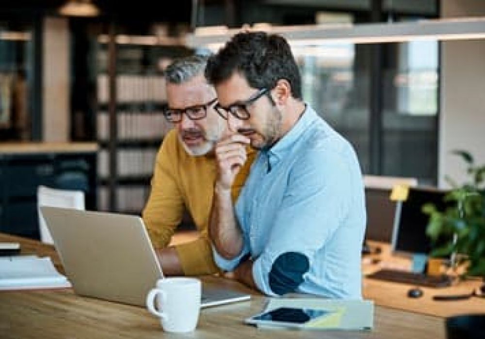 2 businessmen looking at laptop thinking about insurance concerns of business